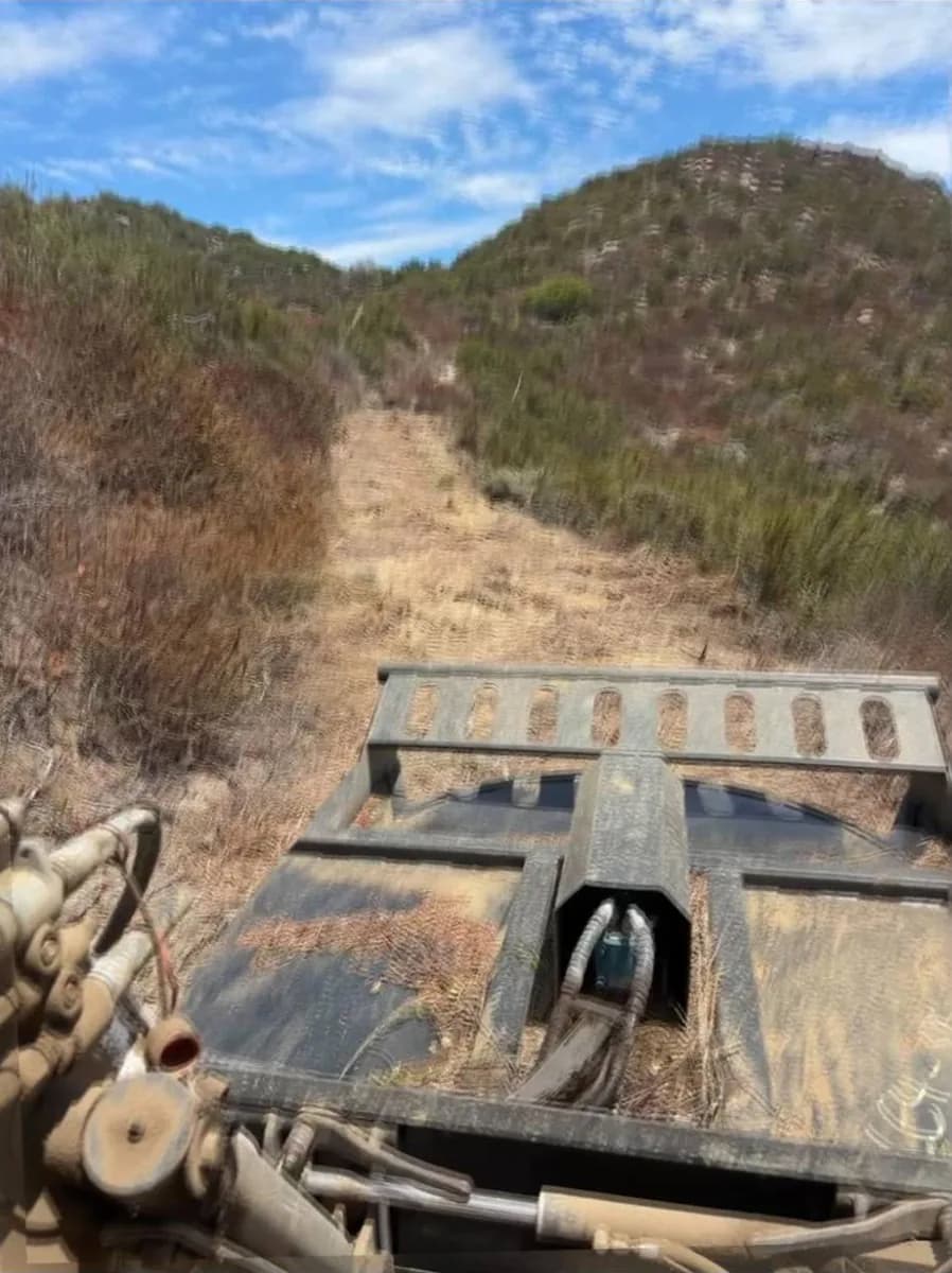 Bobcat T300 brush cutter mowing a fire break up a steep chaparral hillside